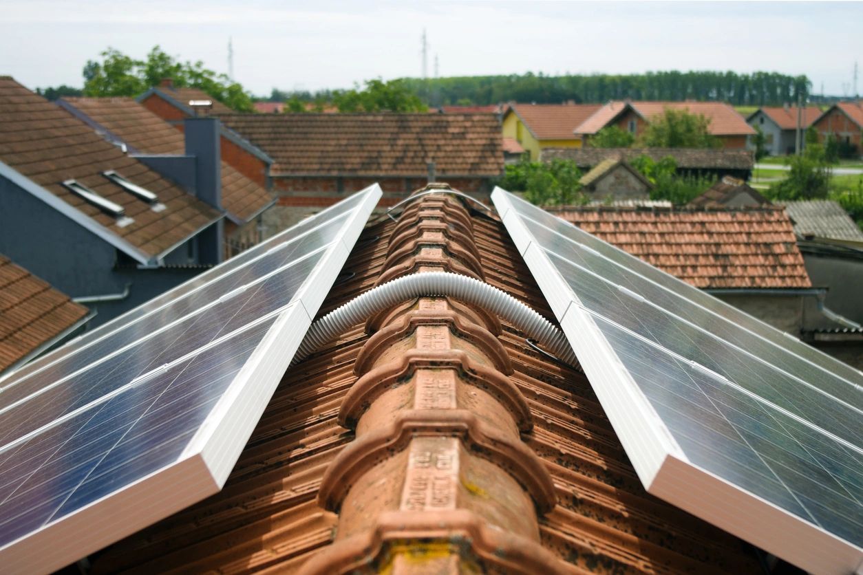 Solar panels installed on a tiled rooftop in a residential area.