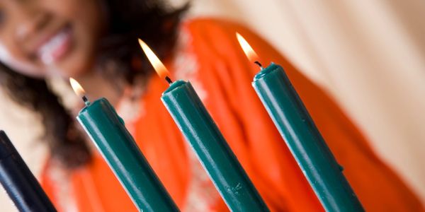 Lit green candles with a smiling woman in the background.