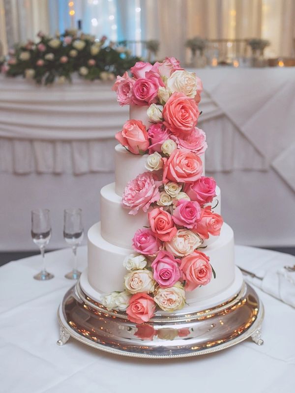 Elegant white tiered cake adorned with cascading pink and white roses.