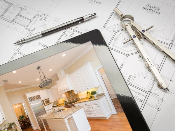 Tablet showing a modern kitchen on architectural blueprints with drafting tools.