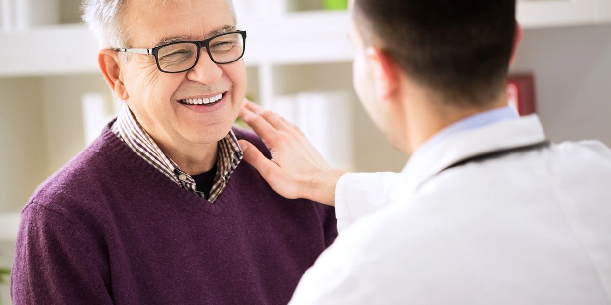 Doctor warmly examines a happy elderly man in a clinical setting.