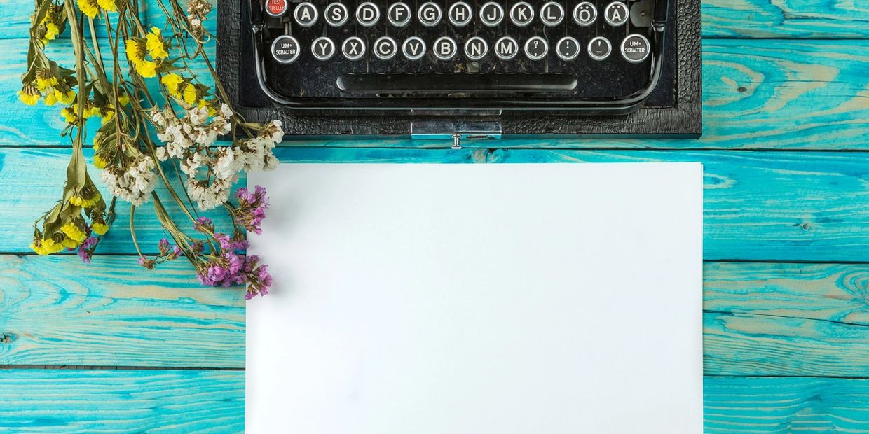 Typewriter on a wooden table with dried flowers