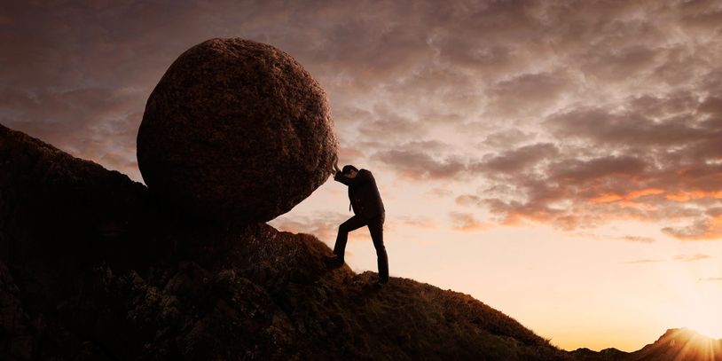 Person pushing boulder uphill at sunset — anxiety therapy for adults in Florida.