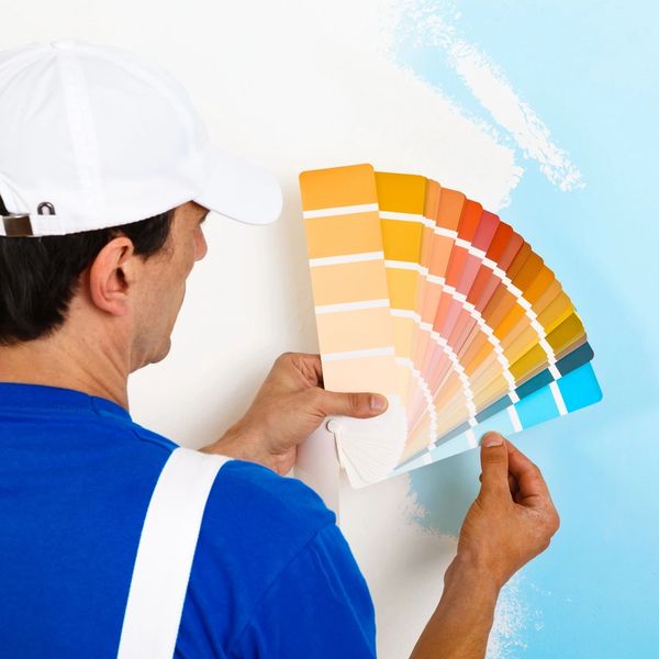 Painter comparing color swatches to a freshly painted wall.