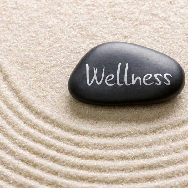 Black stone with 'Wellness' on sand with concentric circles.