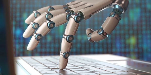 A robotic hand typing on a laptop keyboard in a futuristic setting.