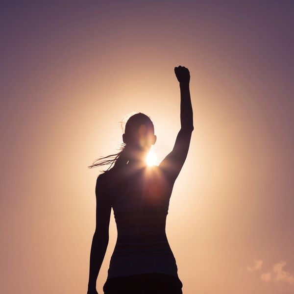 A silhouette of a woman raising her hand 