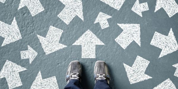 Someone looking down at the floor that is filled with many arrows. The arrows are pointing in different directions. 