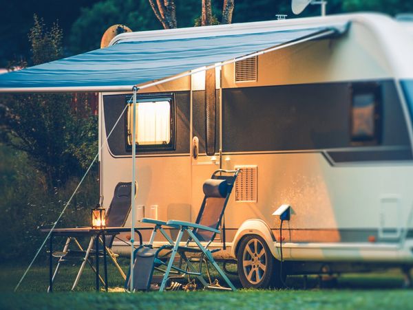 Hunt RV park stock photo of a camper with two chairs, table, night light and awning out.