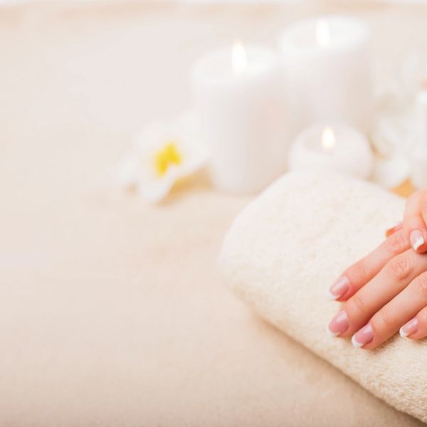 Relaxing spa setting with hands, towel, and candles.