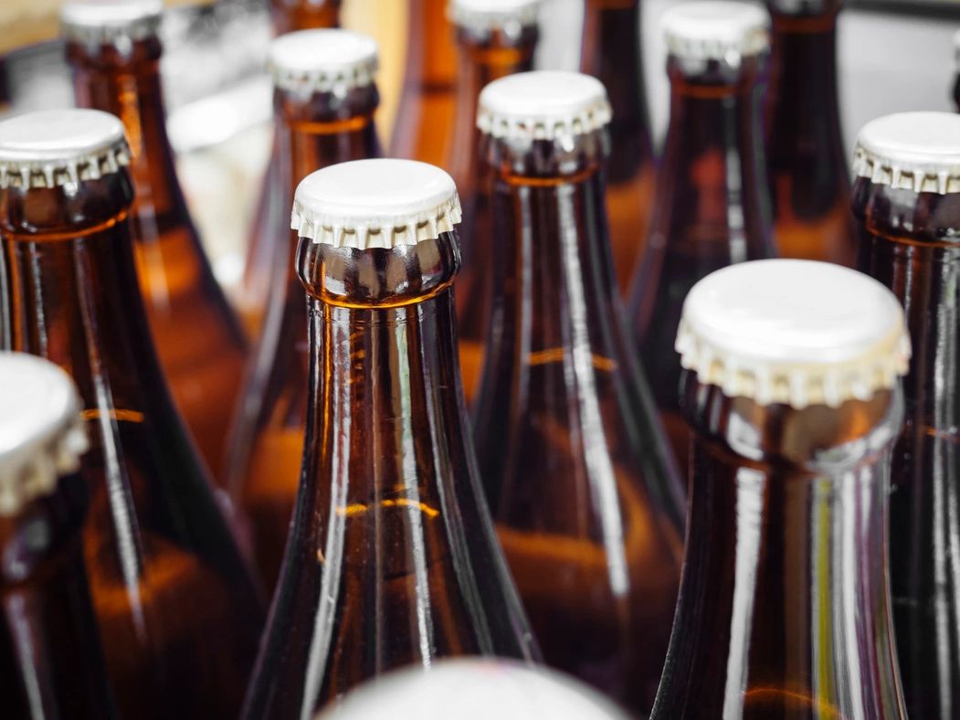 Close-up of brown glass beer bottles with white caps.