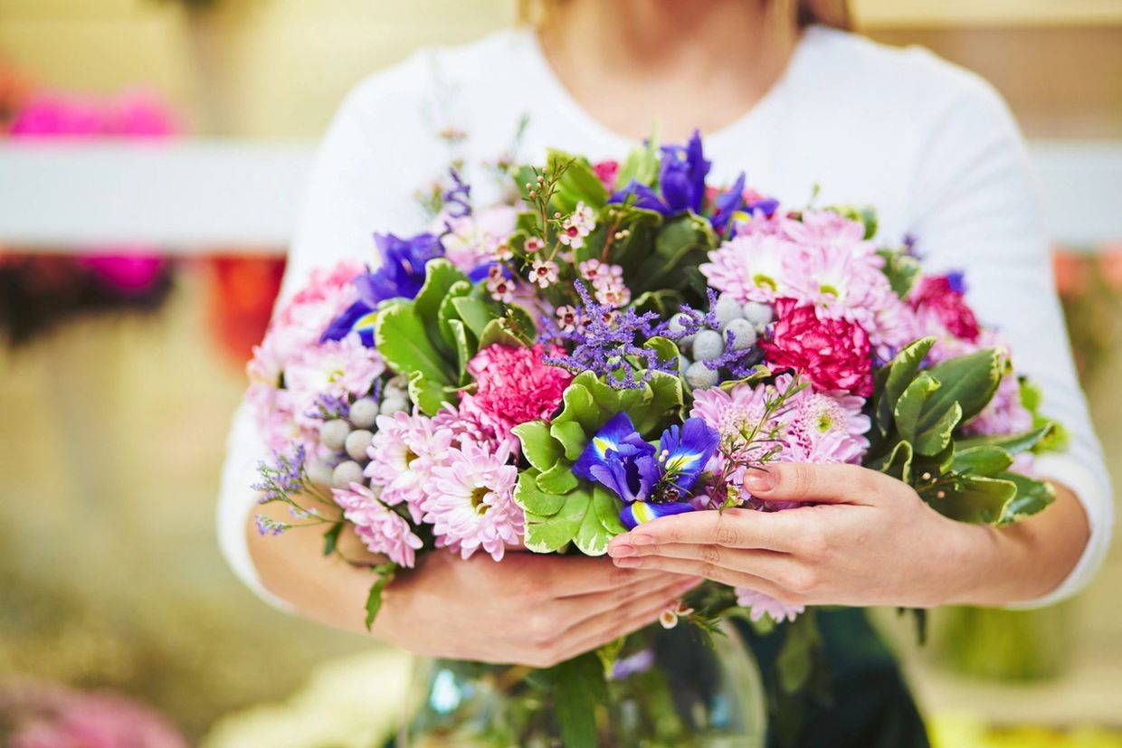 Person holding a colorful bouquet of fresh flowers.