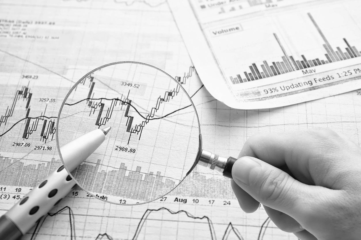 Magnifying financial charts with pen and magnifying glass for detailed analysis.