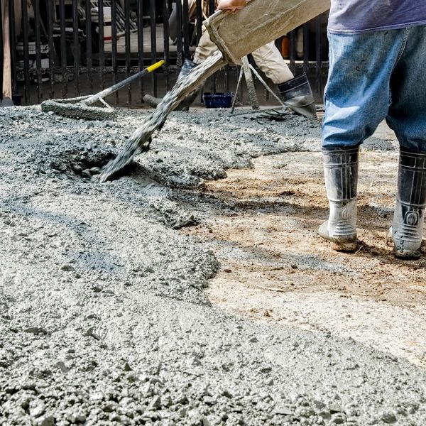 Construction workers pouring concrete on the ground.