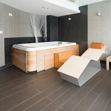 Modern spa room with a wooden jacuzzi and sleek lounge chair.