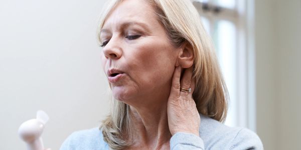 Woman with fan blowing on face and neck