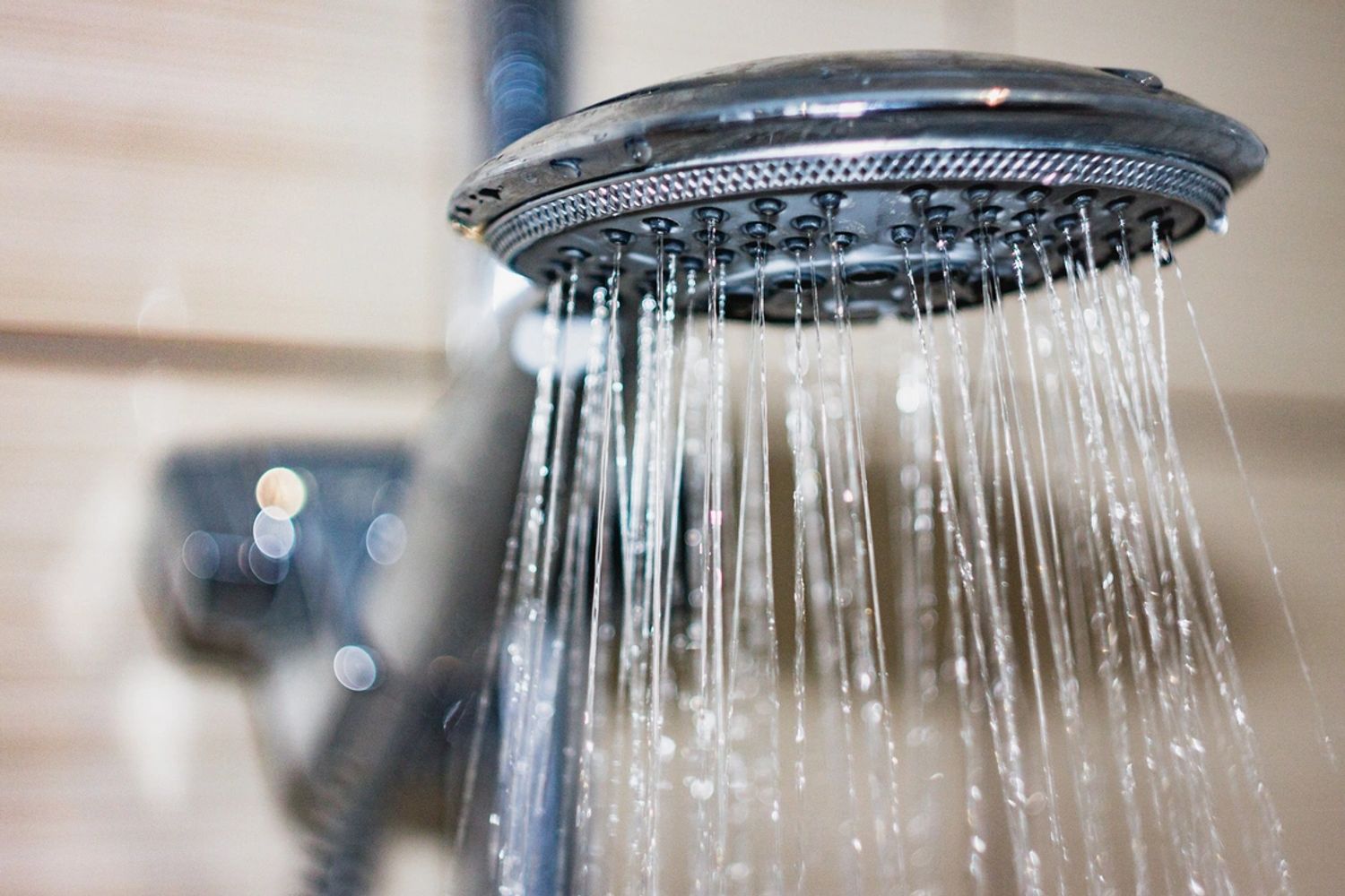 A new, stainless steel shower head gently spouting water.