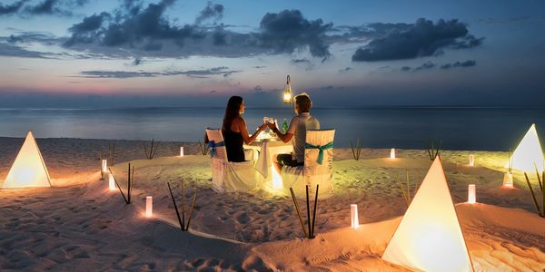 Gennady Podolsky - Beachside dinner for two, with lights, sand and a sunset providing ambiance.