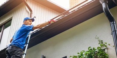 Man cleaning gutters from ladder