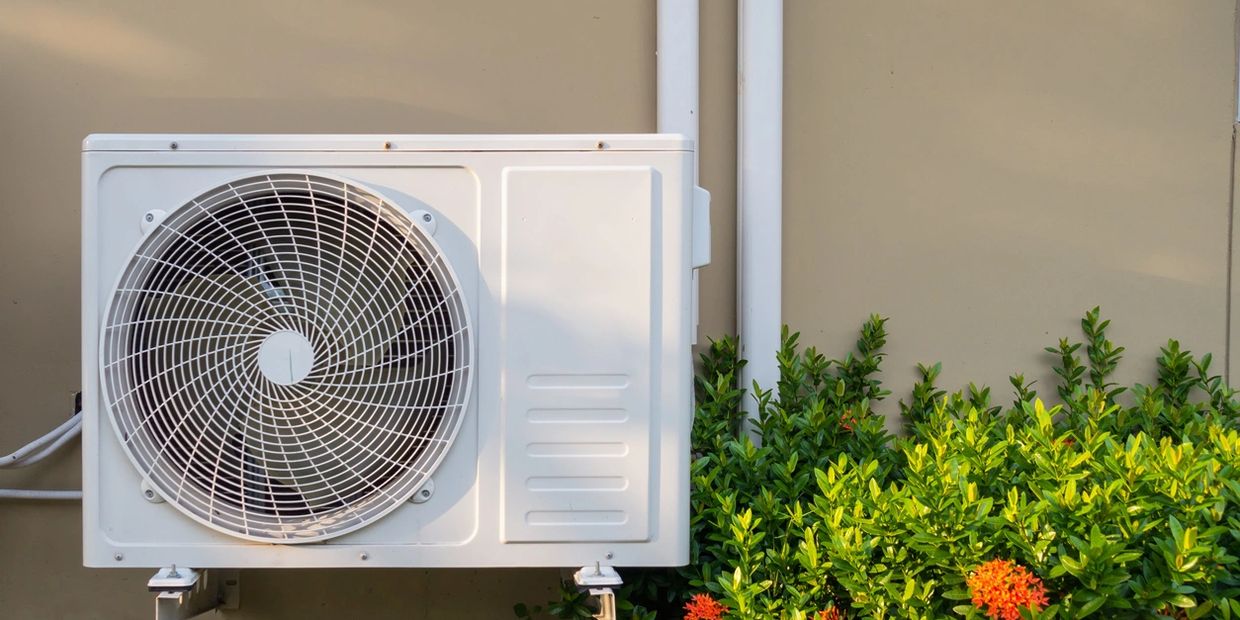 A outdoor air conditioner unit near the plants 