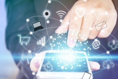 Person using a smartphone with digital icons representing connectivity and technology.