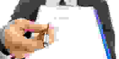 A businessman wearing a tie offering a pen and document to be signed.