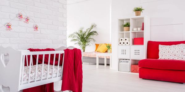Bright, cozy nursery with a white crib and red accents.
