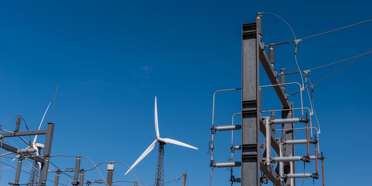 Wind turbines and electrical infrastructure under clear blue sky.