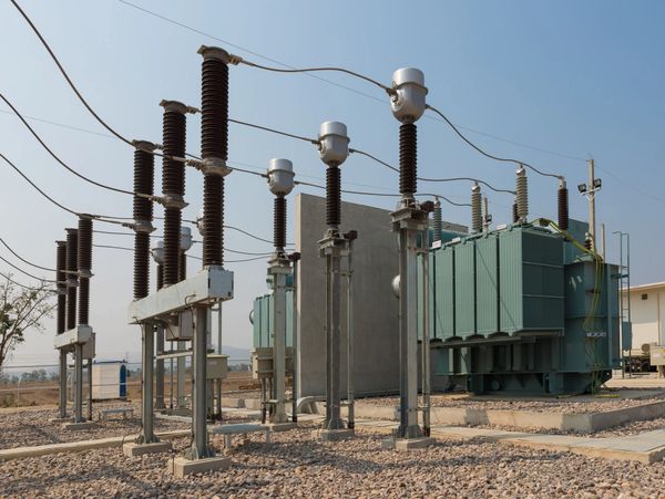 Electrical substation with transformers and insulators under clear sky.