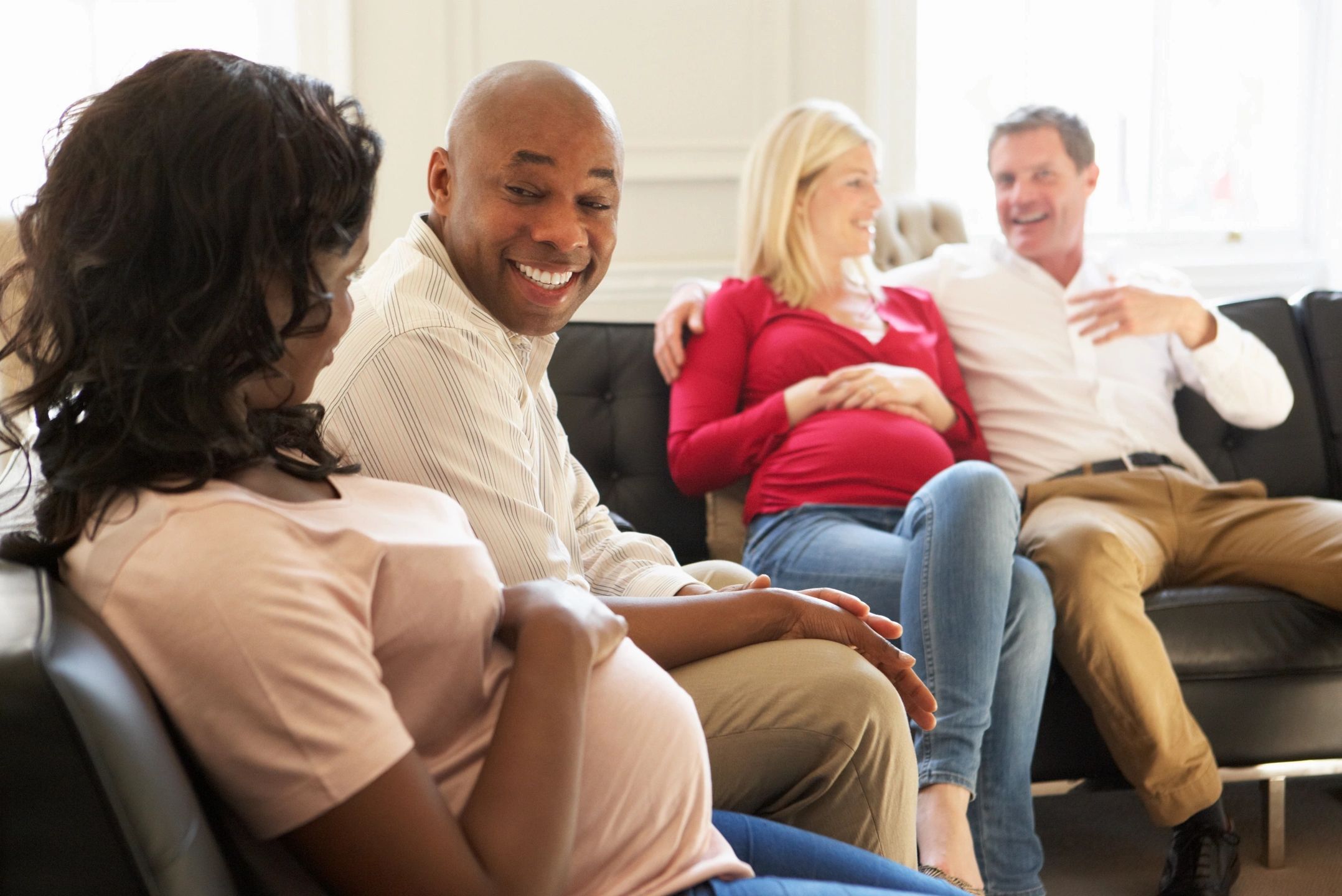 Two couples sitting and chatting, two women visibly pregnant.