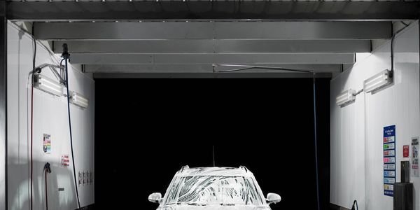 Coche en autolavado con espuma blanca.