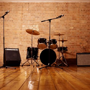 Showcasing a rehearsal space for drums, guitarist, and a vocalist
