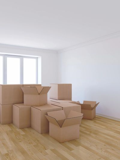 Stack of cardboard moving boxes in an empty room with wooden floor.
