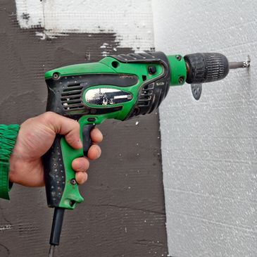 A person drilling in a wall with driller