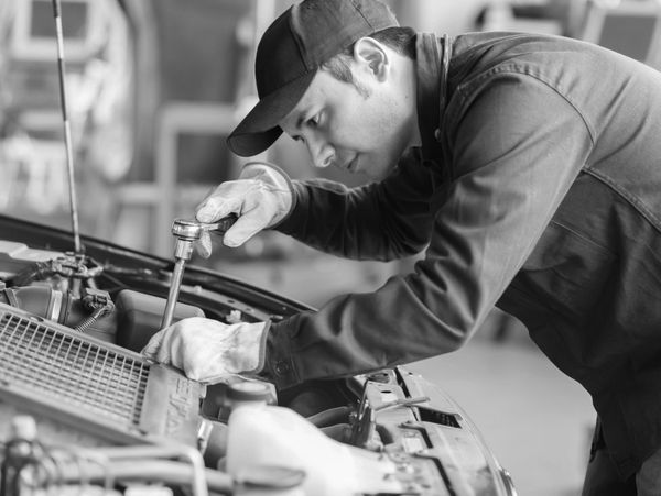A mechanic focused on repairing a car engine using a wrench.