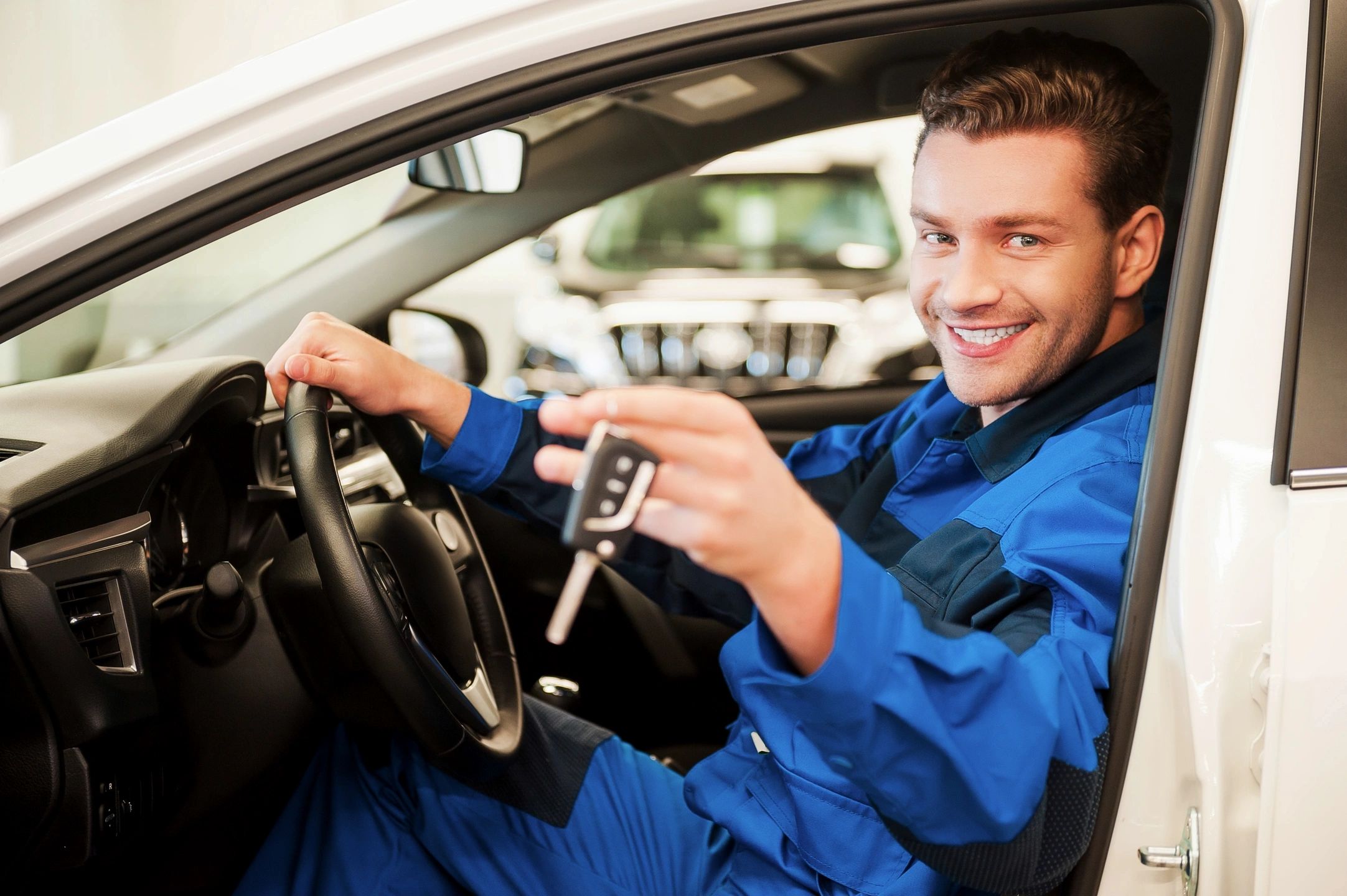 Happy man sitting in driver seat of a car holding up car keys