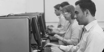 People working intently at computers in an office setting.