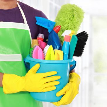 Hands of a woman holding cleaning products inside a bucket.