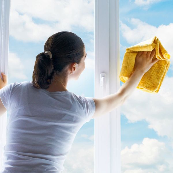 Woman cleaning a window with a yellow cloth.