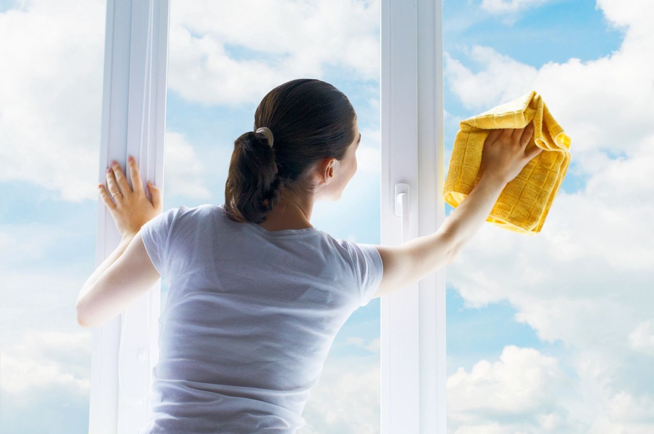 Home Routine Housework Concept A Woman Clean A Window Pane With A Squeegee  And Soap Suds Hands In Pink Protective Gloves Cleaning Glass On The Windows  With A Detergent Spray Bottle Copy
