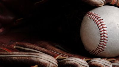 Baseball and glove close-up on a dark background.
