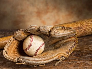 Worn baseball glove holding a ball, showing expert Baseball Glove Break In Service.