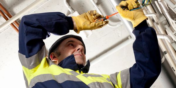 Local electrician wiring new electrical cables into a warehouse. 