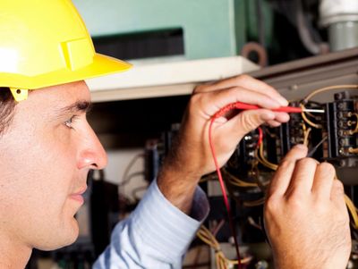 Electrician in a yellow helmet working on wiring.