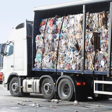 Truck loaded with compacted recyclable paper and cardboard bales.