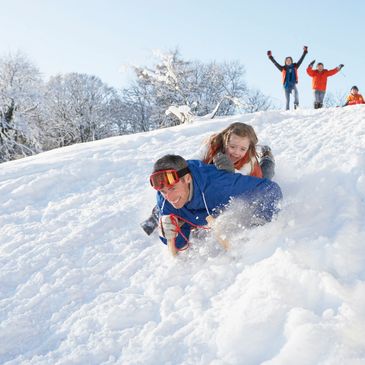 Two children sledding down a snowy hill with joy.
