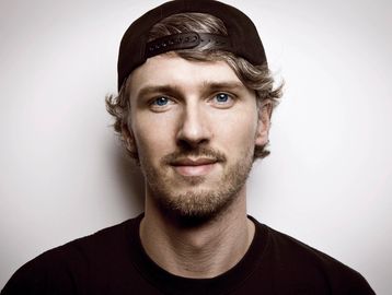 Young man with blue eyes and a backward cap.