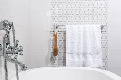 White bathroom with towel, wooden brush, and chrome faucet.