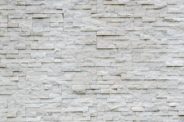 White textured stone wall with staggered rectangular blocks.