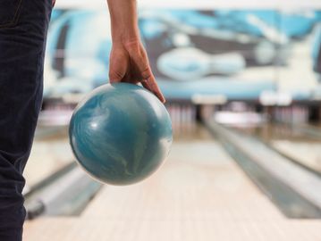 Person holding a bowling ball ready to bowl.